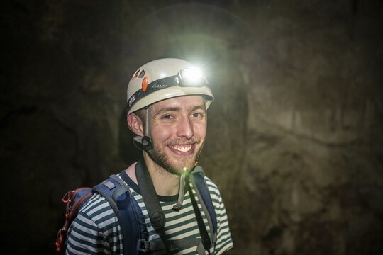 Young man with helmet and headlamp in a stalactite cave, Terciopelo Cave, Barra Honda National Park, Costa Rica