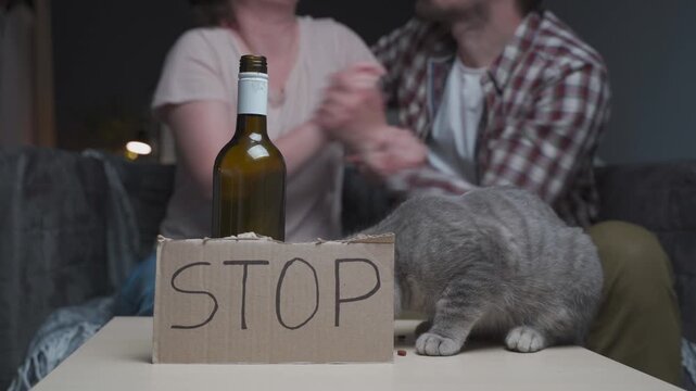Close-up of a hungry cat feeding itself on a table next to an alcohol bottle, capturing a dramatic concept of family violence and severe pet neglect.