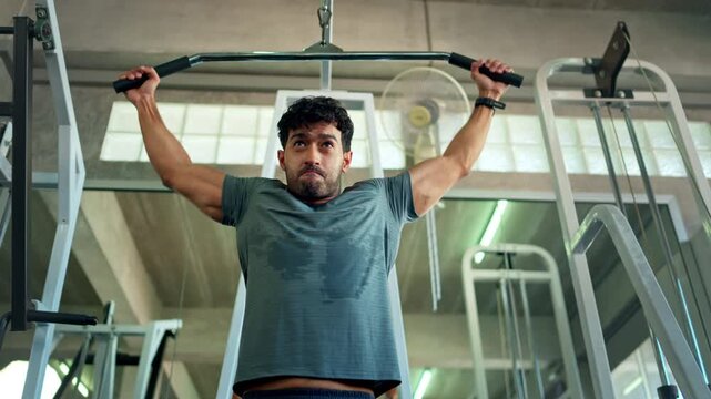 Athletic man performing a lat pulldown exercise on a strength training machine in a fitness center
