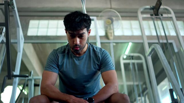 Athletic man performing resting after a lat pulldown exercise on a strength training machine in a fitness center