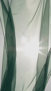 Vertical video: Sun rising at window, sheer curtain with dark ribbons rippling by draft, sun flare