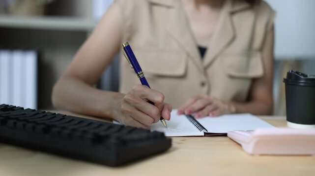 Close-up of businesswoman hands writing notes and taking minutes in a notebook during a meeting, showcasing professional dedication and meticulous record-keeping