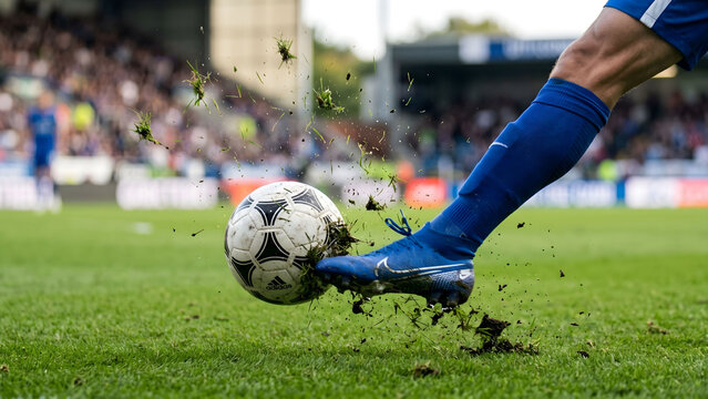 Action shot of a soccer ball being kicked by a player on a grass pitch