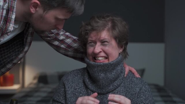 Dramatic footage of injured woman showing severe facial injuries and a missing tooth while her abusive, alcoholic spouse stands over her in dark room. Brutal impact of domestic violence and alcoholism