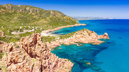 Obraz premium Aerial drone view of the Marina di Gairo coastline, Sardinia. Turquoise Mediterranean waters meet striking red granite cliffs, creating a wild and unspoiled coastal landscape.