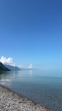 Calm Black Sea pebble beach with green mountains in Gonio, Georgia