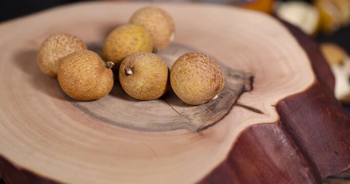 peeled longan fruit from the shell, a table with ripe fruits that are peeled from the shell and put in a bowl and scattered on the table in the shell, dry longan