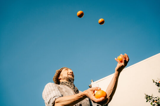 Juggler Performs With Oranges Outdoors Under a Clear Blue Sky
