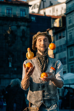 Juggler in a Busy Square Entertains Crowd With Oranges and a Parrot