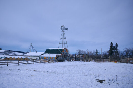 Windmill Stands Watch Over Snowy Farm Landscape in Winter
