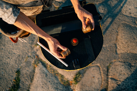 Man Holds Items in Hands While Standing on Stone Road