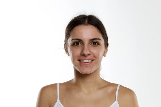 Studio portrait of smiling brunette woman with no makeup and natural beauty on white background.
