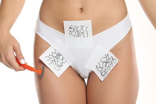 Close-up of a woman&rsquo;s bikini zone in white panties holding a razor with hair growth concept cards for shaving and depilation, studio shot on a white background
