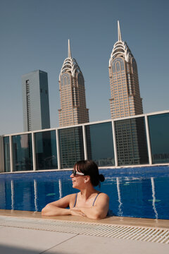 Portrait of a happy woman in sunglasses swimming in the rooftop pool