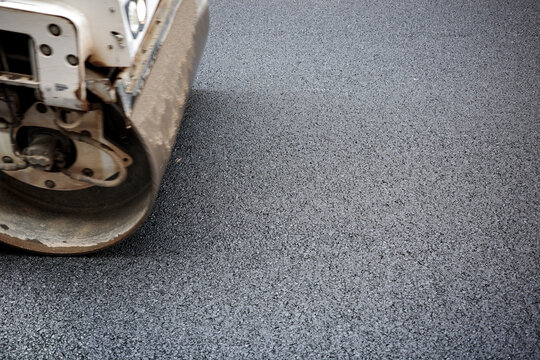 Steam roller drum pressing fresh asphalt 