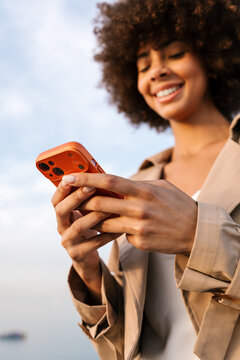 Woman smiling while using smartphone outdoors