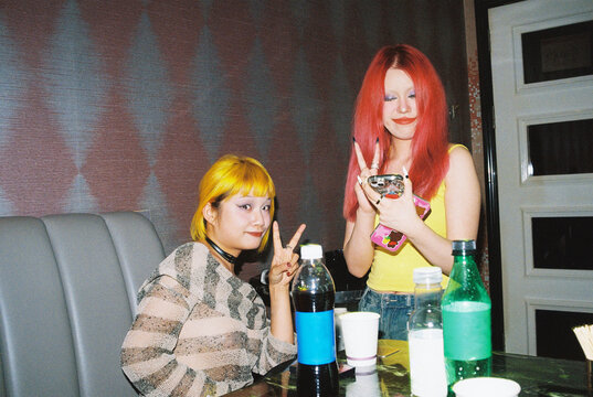 Two young women with bold dyed hair posing at a karaoke