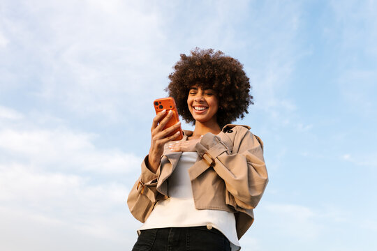 Young woman smiling using smartphone outdoors