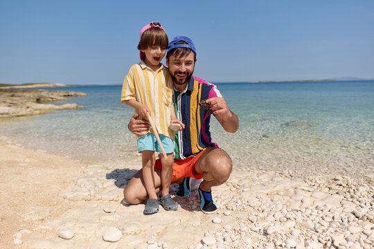 Father and child exploring shells on beach