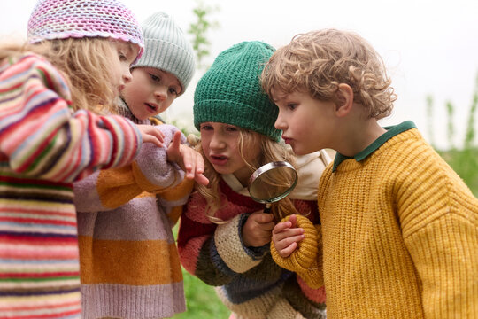 Children Investigating Nature With Magnifying Glass