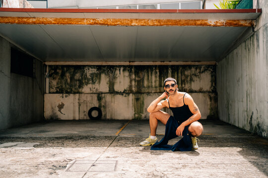 Man Squats in an Empty Parking Garage Wearing Athletic Wear