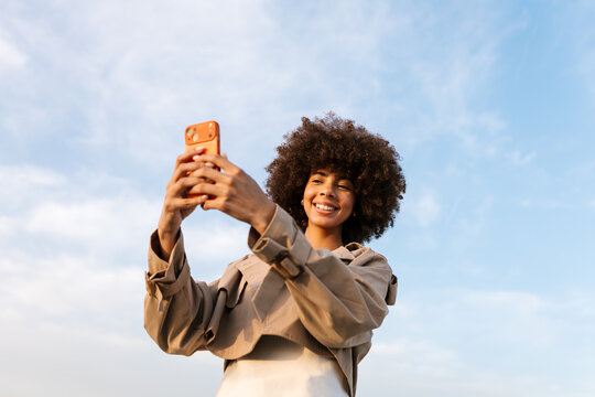 Happy woman recording video on smartphone outdoors