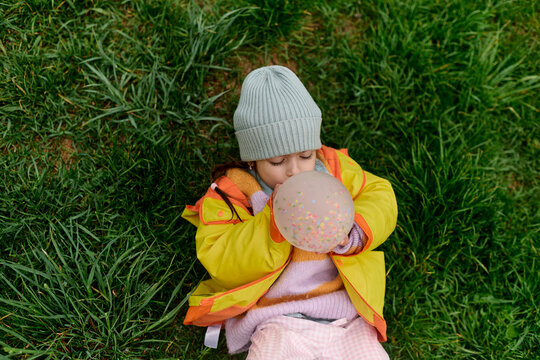 Child Blowing Confetti Balloon Outdoors