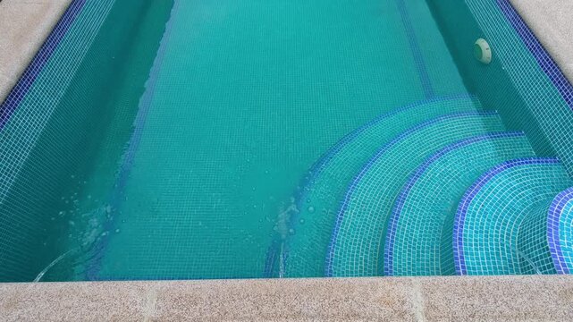 High-quality video of swimming pool water with fountains pouring into turquoise tile steps