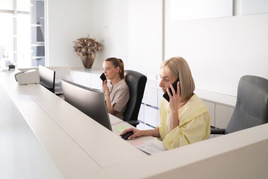 Two Receptionists Work at Their Desks in a Modern Office