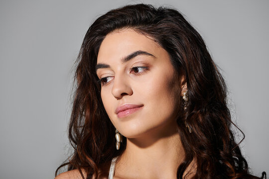 Young woman poses gracefully, highlighting her curly hair and natural beauty in soft lighting.