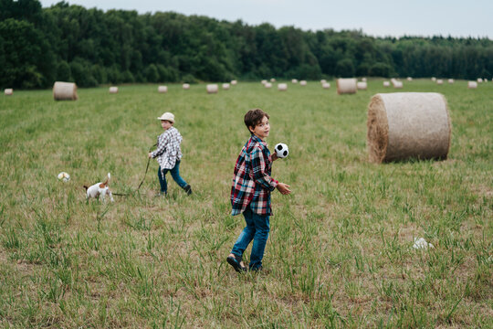 Children Play Soccer in a Lush Green Field With Hay Bales