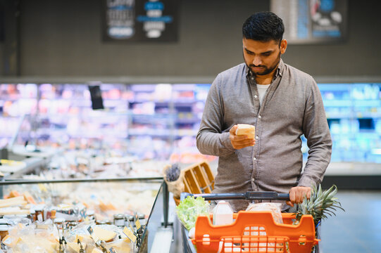 Man comparing cheese while shopping in grocery store