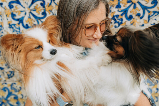 Close up portrait of woman cuddling two Papillon dogs