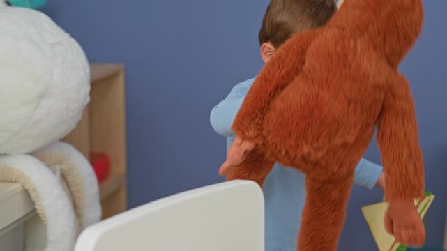 Boy holding a stuffed monkey and placing a toy sandwich on a table, hand extended toward a brightly colored playroom scene; playful imagination.