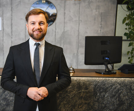 Male hotel receptionist welcoming guests at reception desk
