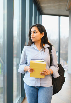 Indian female student walking through university campus hallway