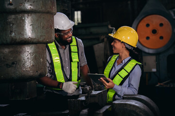 Fototapeta premium Group of professional mechanical technicians and engineers performing routine maintenance, inspecting components, and checking machinery on a factory plant site.