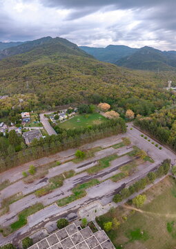 Aerial view of a large paved parking lot surrounded by lush green trees and rolling hills under a cloudy sky in Islamabad, Islamabad Capital Territory, Pakistan.