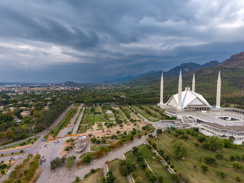 Aerial view of Faisal Masjid surrounded by lush greenery and the Margalla Hills under a dramatic cloudy sky in Islamabad, Islamabad Capital Ter, Pakistan.