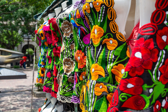 Traditional Mexican embroidered blouses with colorful floral patterns at artisan market