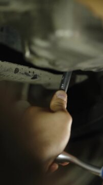 Mechanic uses a socket ratchet wrench tool under car engine