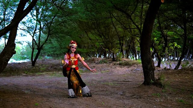 Woman in ornate traditional costume performs graceful dance sequence along dirt path inside shaded forest park, moving from still pose into flowing gestures