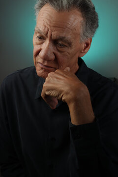 Older Senior Man looking serious with his hand on his chin in deep thought