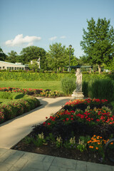 Fototapeta premium Curving garden pathway leading through colorful flower beds and manicured landscaping in the Sunken Garden at Phillips Park Sunken Garden in Aurora, IL