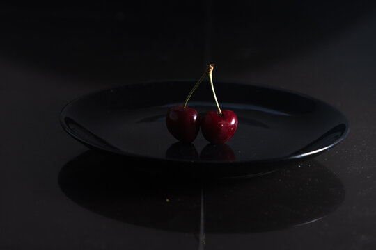 two fresh ruby cherries on black background