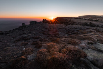 Obraz premium Rocky mountain peak at sunset with warm orange light on stones