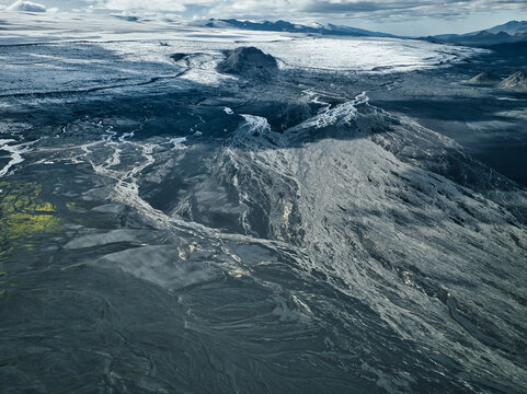 Aerial view of the volcanic landscape near Maelifell, featuring dark lava fields, glacial rivers, and distant ice caps in Kirkjubaejarklaustur, Skaftarhreppur, Iceland.