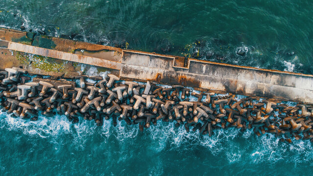Aerial view of a concrete breakwater reinforced with numerous tetrapods protecting the coastline from crashing turquoise ocean waves, Santo Domingo, Dominican Republic.