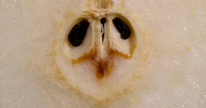 A round yellow sliced pear, segmented pear fruit is located on a wooden substrate next to massive pieces of light pulp.