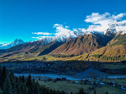 Aerial view of rugged Caucasus mountain range with deep valley and scattered clouds in Svaneti Georgia